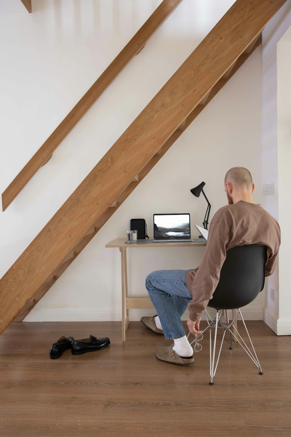Hombre trabajando en un portátil en un escritorio debajo de una escalera.